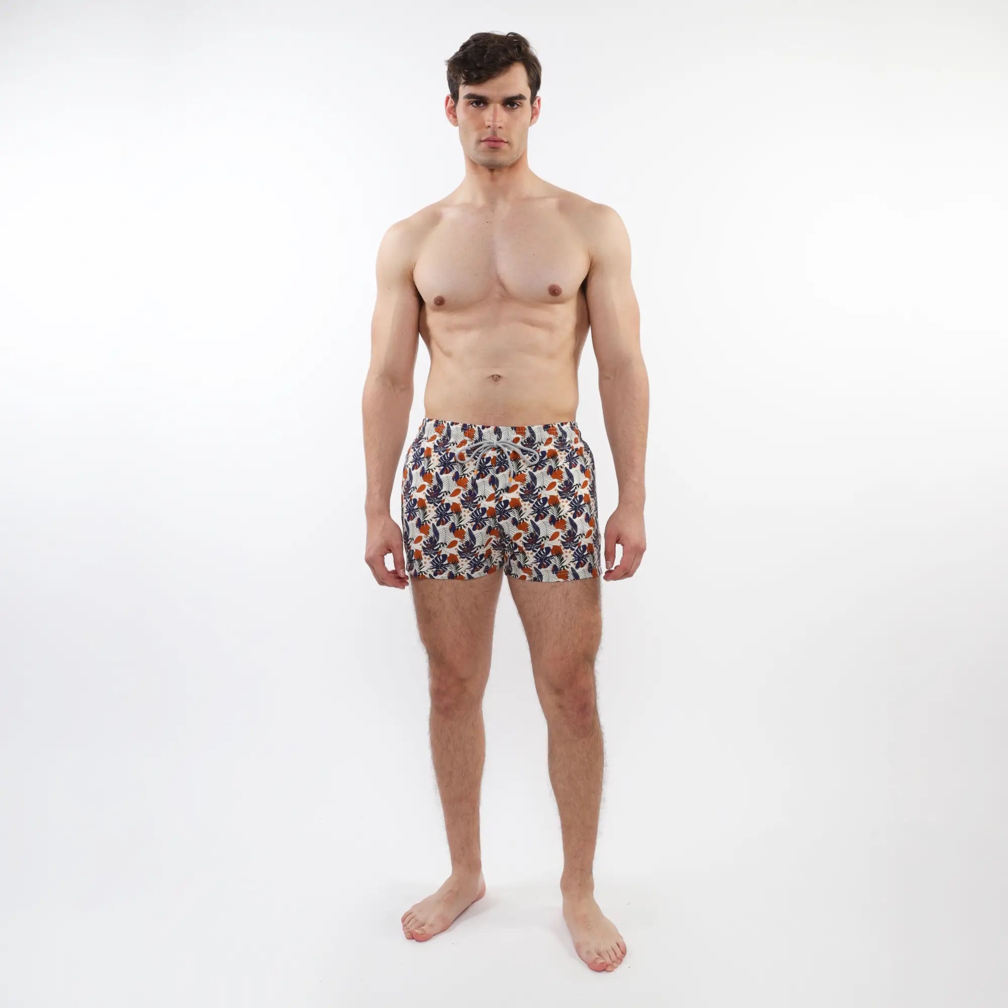 Men’s printed swim shorts with mesh lining featuring vibrant orange navy and white tropical leaf and fruit pattern on light fabric