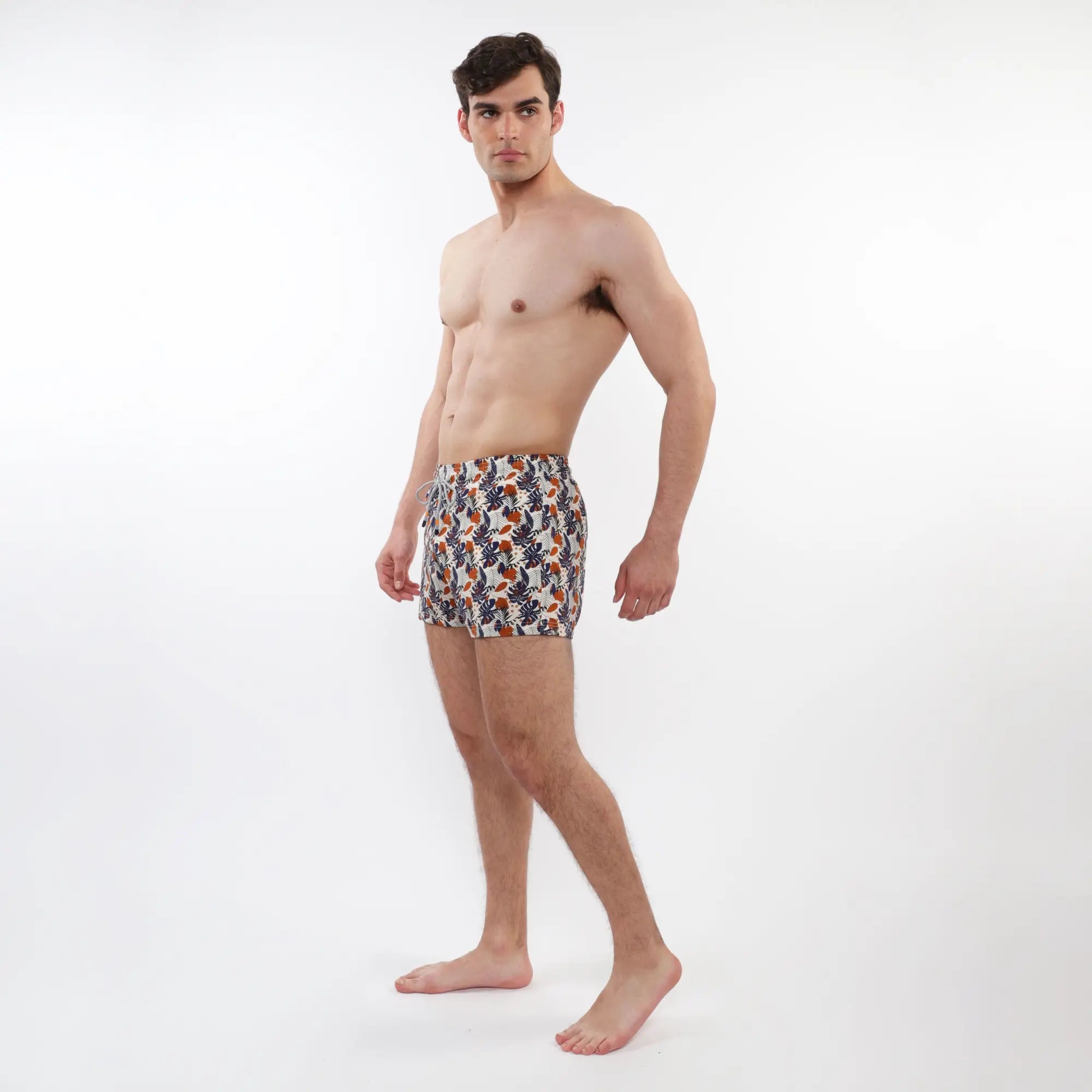 Men’s printed swim shorts with mesh lining featuring vibrant tropical orange navy blue and cream leaf pattern on white