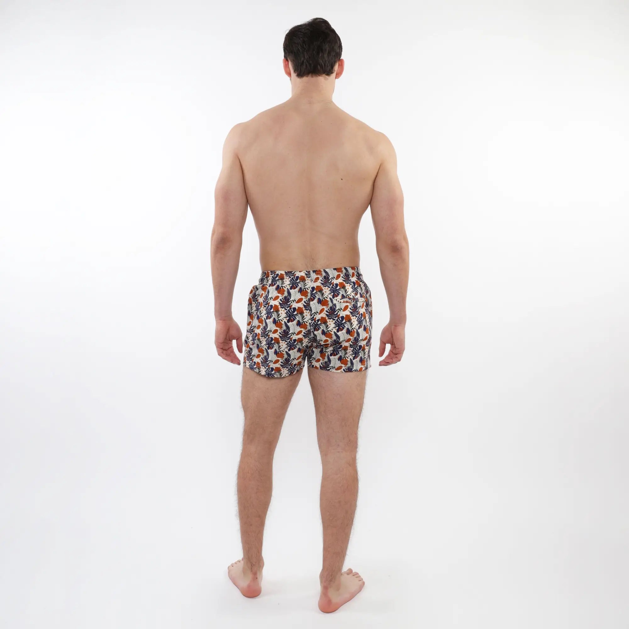 Men’s white printed swim shorts with orange and navy tropical leaf pattern and mesh lining for comfortable wear