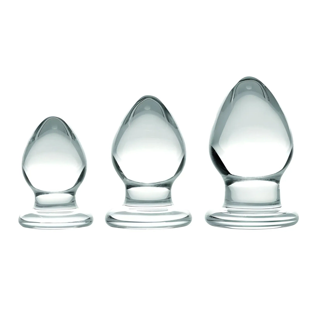 Prisms Erotic Glass 3 Piece Anal Plug Kit featuring three graduated, smooth, clear glass plugs on a white background.