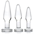 Prisms Erotic 3pc Dosha Glass Anal Plug Kit: Three clear, graduated glass plugs with flared bases on a white background.