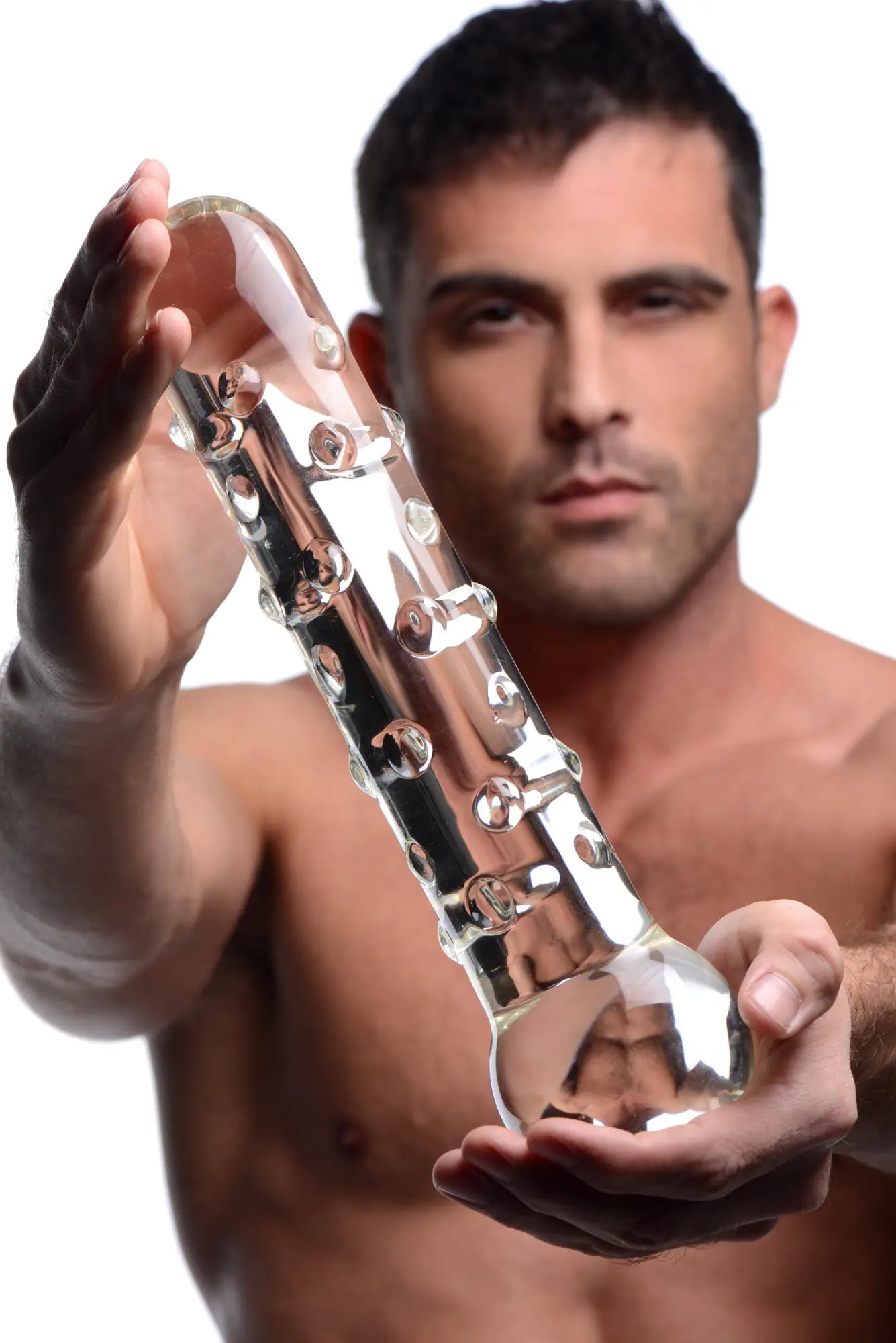 A shirtless man holding the clear, textured Prisms Erotic Glass The Ram toy in front of him.