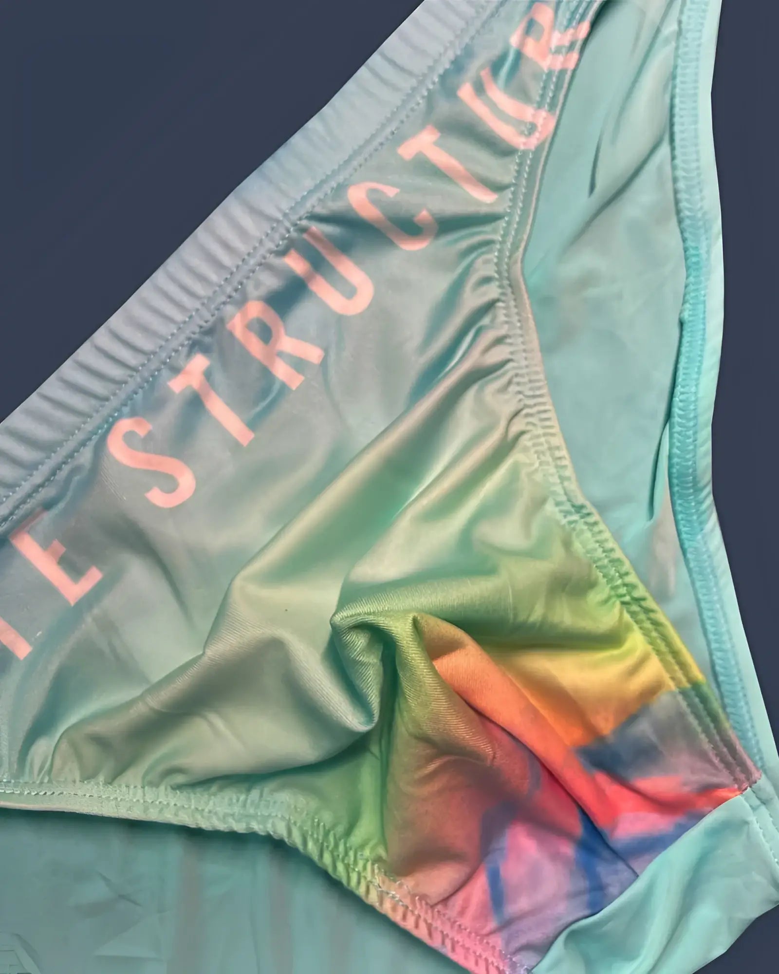 Pastel green tie-dye cyan mist bikini bottom with instructor printed in pink on waistband by private structure