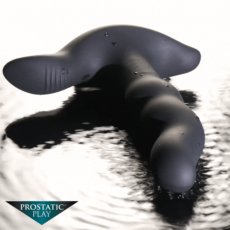 Prostatic Play Rimstatic matte black, curved, ribbed rotating plug resting on a reflective, water-like surface.