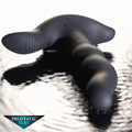 Prostatic Play Rimstatic matte black, curved, ribbed rotating plug resting on a reflective, water-like surface.