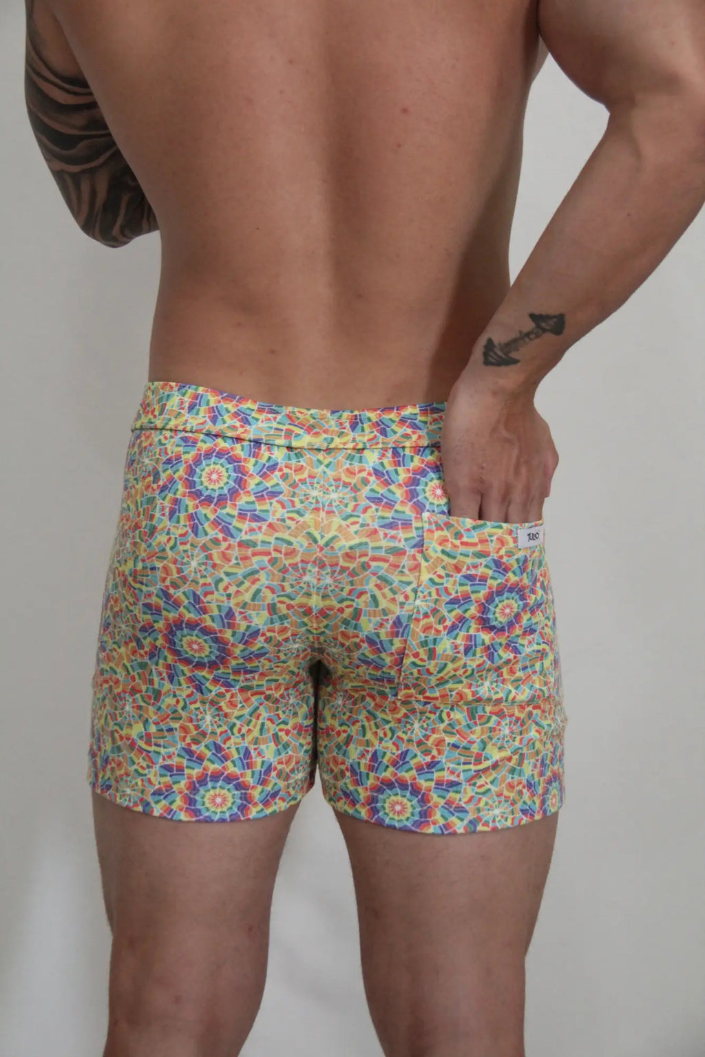 Rainbow kaleidoscope linen texture shorts featuring vibrant multicolored geometric mosaic pattern swim trunks