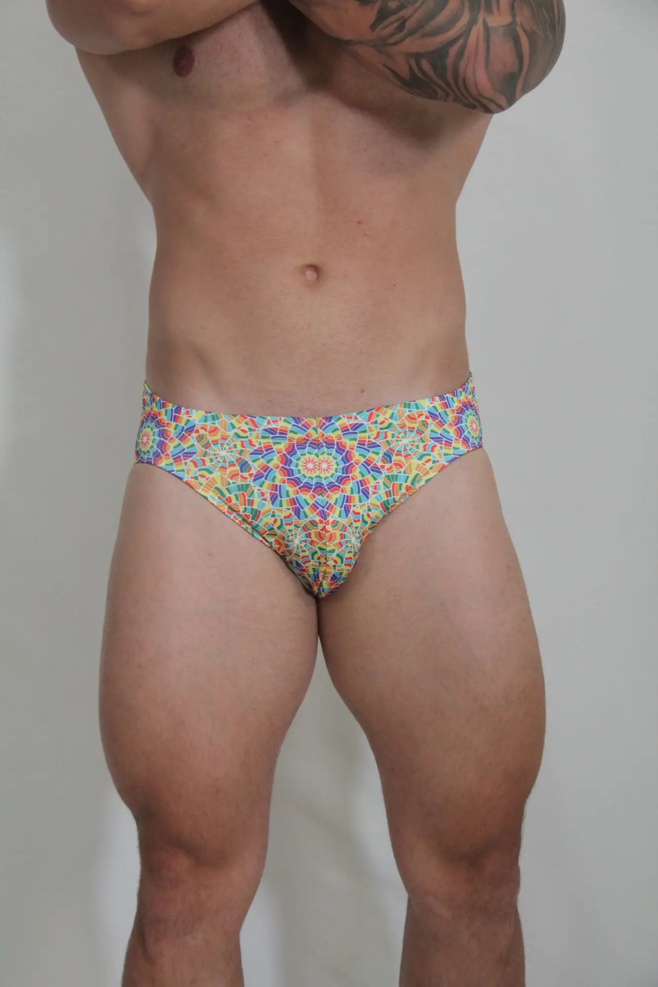 Rainbow kaleidoscope swim brief with vibrant multicolored geometric patterned fabric and bold mandala design