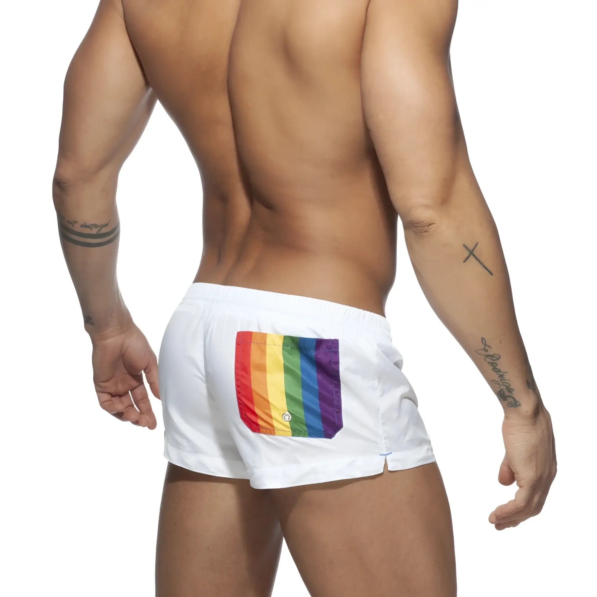 White swim trunks with a vibrant rainbow flag patch on the back pocket shown from the back side