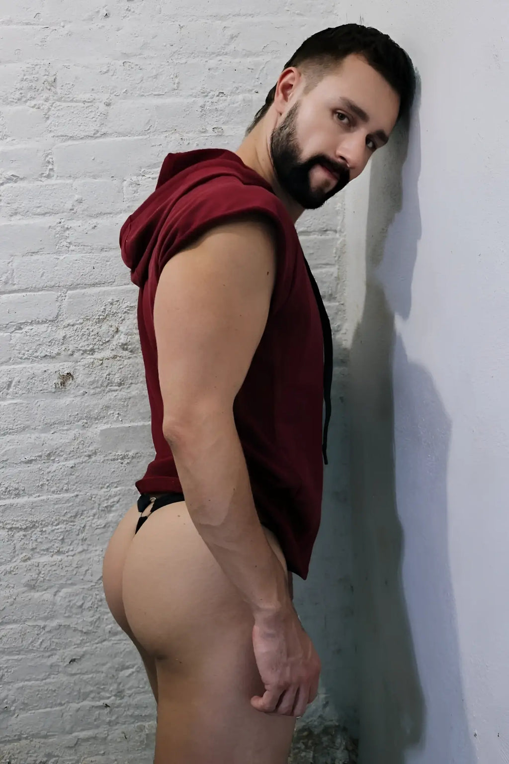 A man wearing a maroon renegade raw sleeveless hoodie with black drawstrings made of comfortable fabric