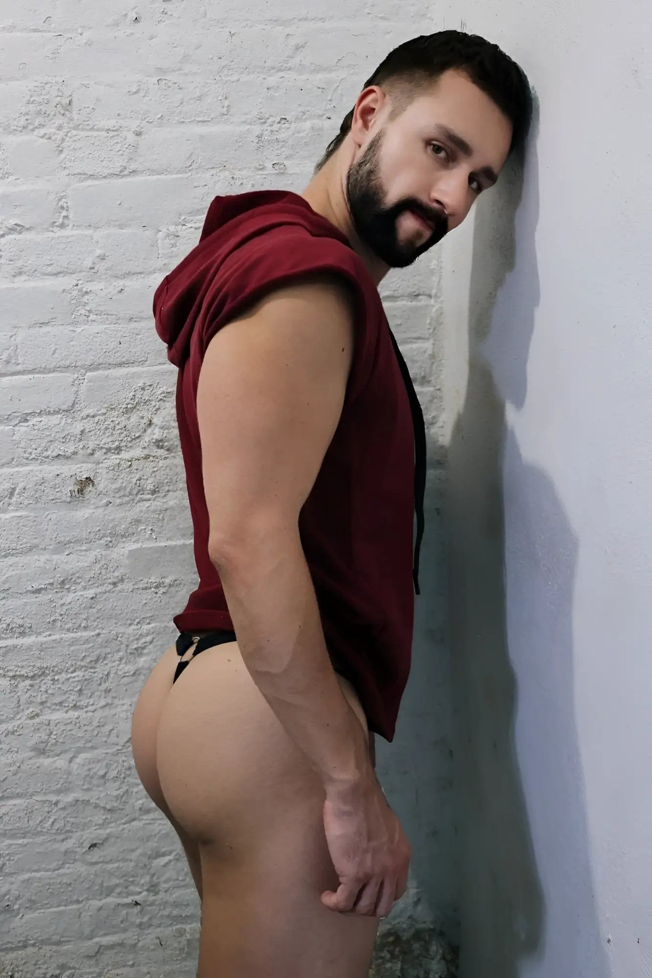 A man wearing a maroon renegade raw sleeveless hoodie with black drawstrings made of comfortable fabric