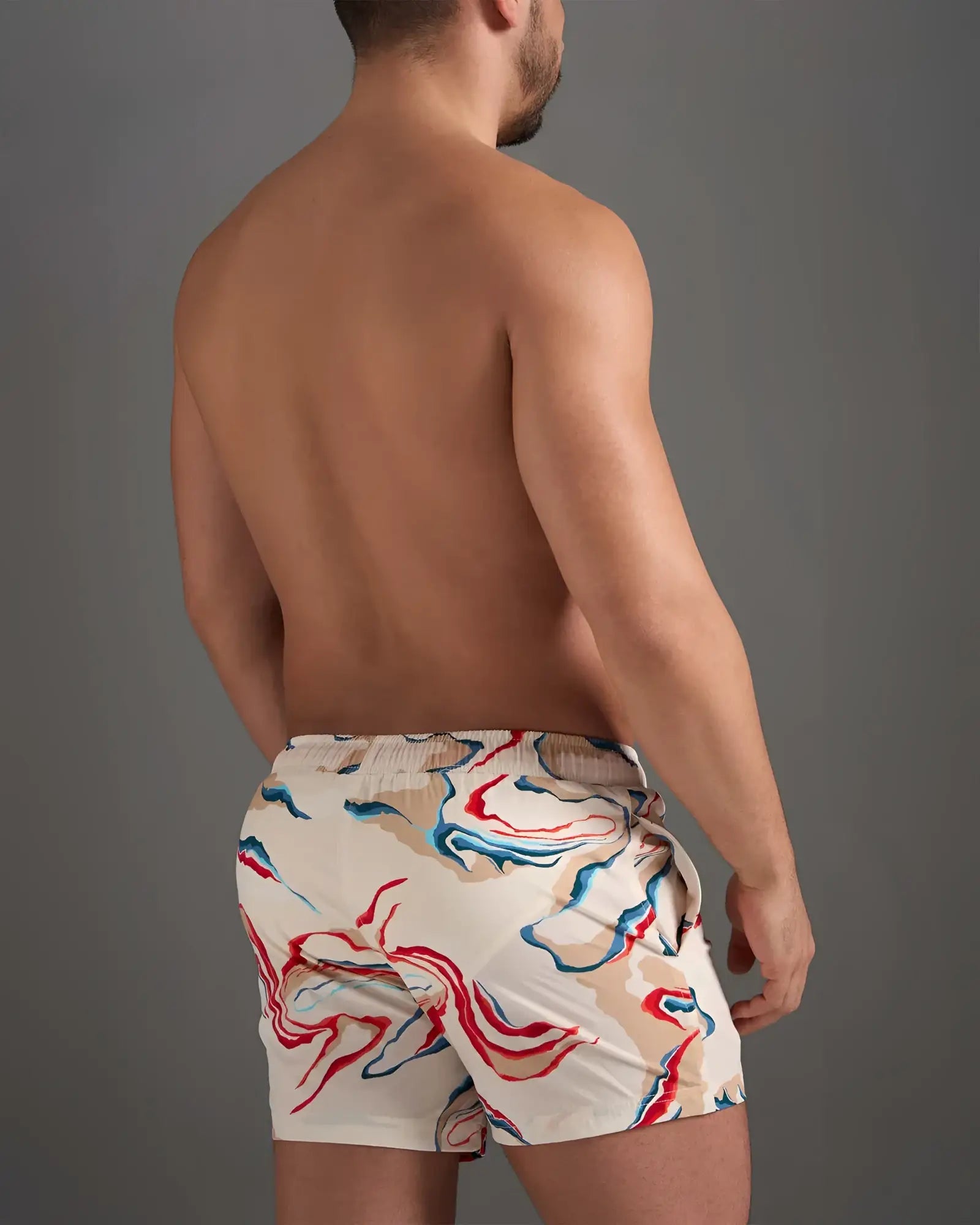 Beige resort swim short with vibrant red blue and white abstract swirl pattern perfect for beachwear