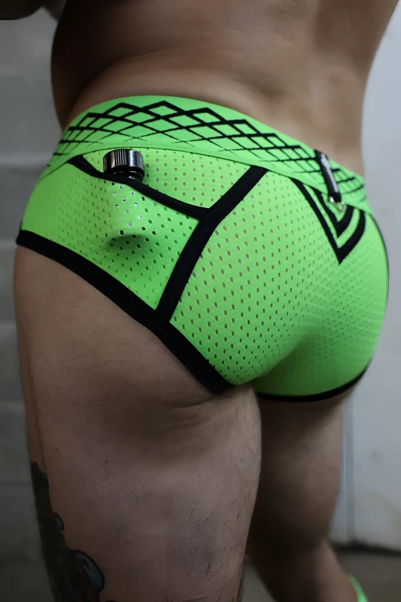 Neon green mesh revolution briefs with black geometric trim and a metallic zipper pull