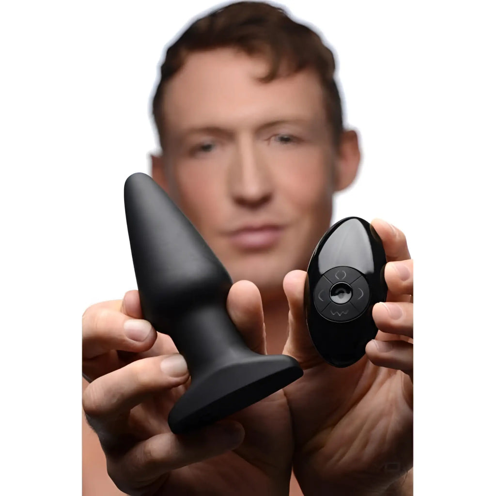 A man holds a smooth, matte black Rimmers Model R plug and its matching glossy black remote control.