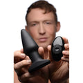 A man holds a smooth, matte black Rimmers Model R plug and its matching glossy black remote control.