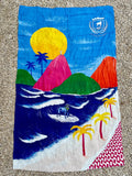 A vibrant Rio Aquarela canga de praia beach towel with colorful surf scene and dog surfing on waves in bright colors