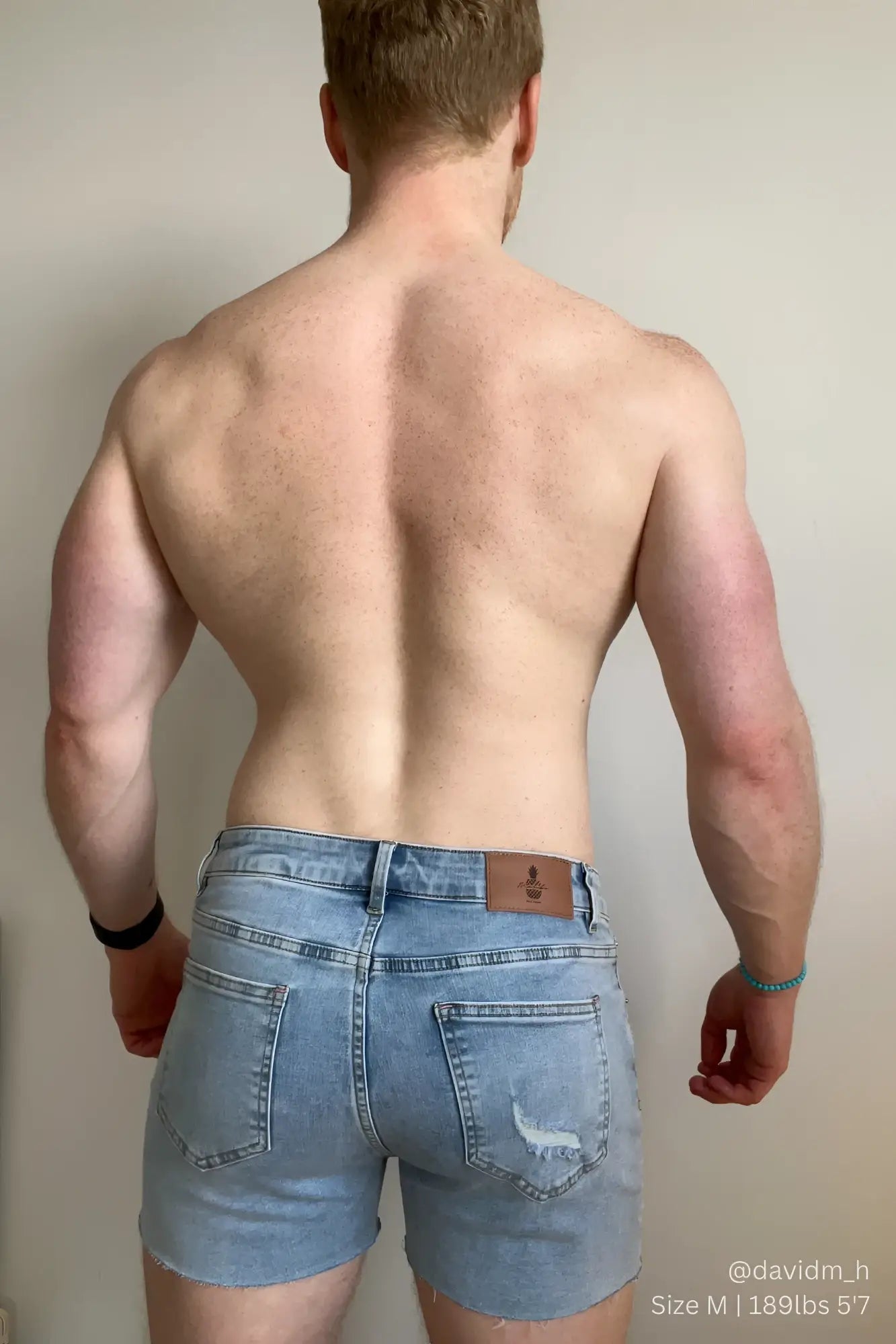 Back view of rockstar raw cut 2.5 inch light-wash denim shorts with distressed back pockets and brown leather patch