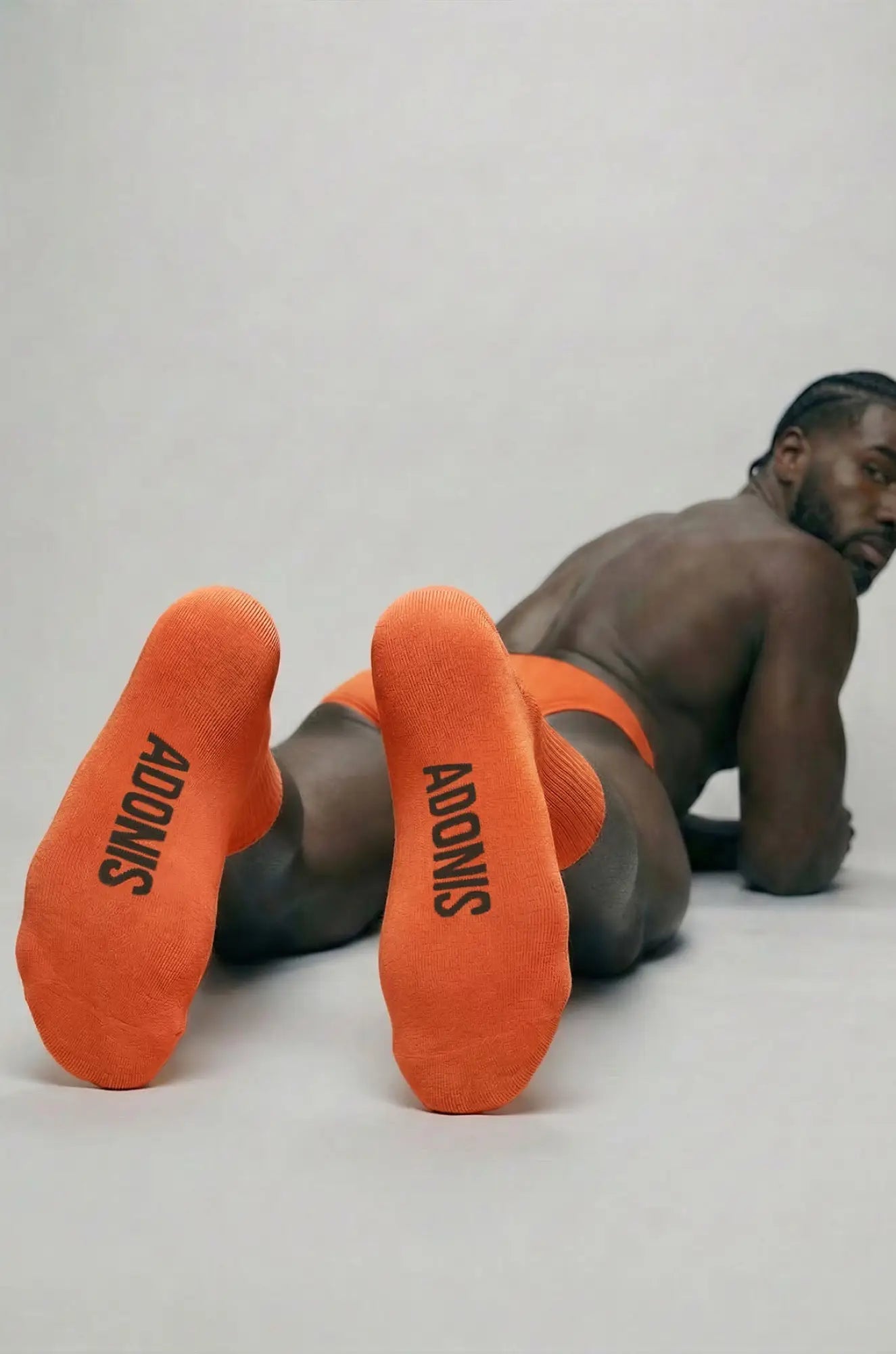 Bright orange rust orange crew sock showing back side with adonis printed in black on the heel