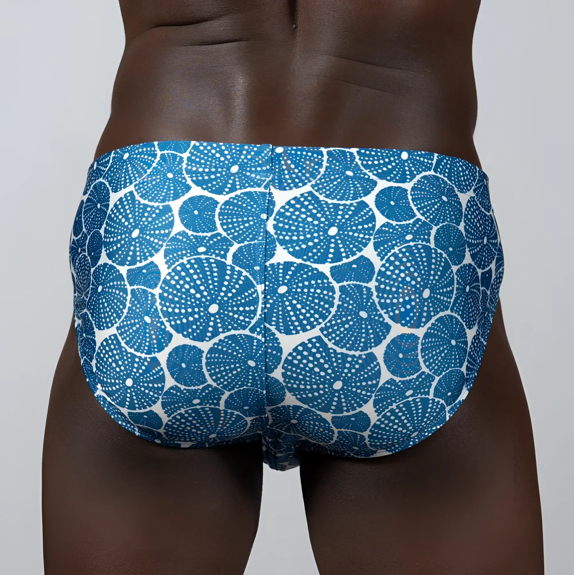 Blue and white patterned swim trunks with repeating circular dotted sea urchin motifs called sand dollar brief