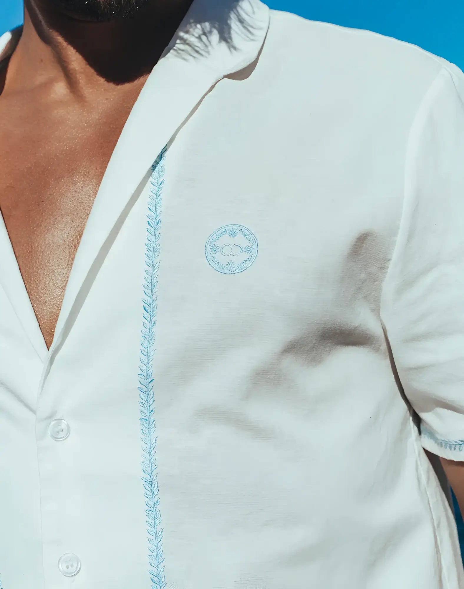 Santorini linen shirt in white with light blue embroidered detailing on the placket and matching chest logo