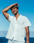 White Santorini linen short-sleeved shirt with light blue embroidery and a small circular logo on the left chest