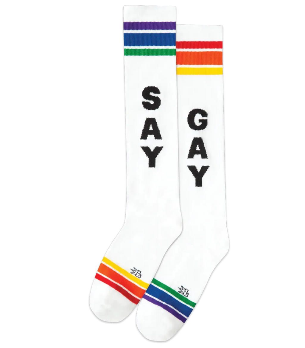 White knee high cotton socks with bold black say and gay lettering and rainbow stripes at top and toe for pride wear
