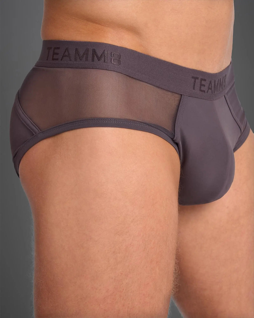 Dark gray score sheer brief with mesh front, solid back, and elastic waistband featuring teamm8 logo visible from back