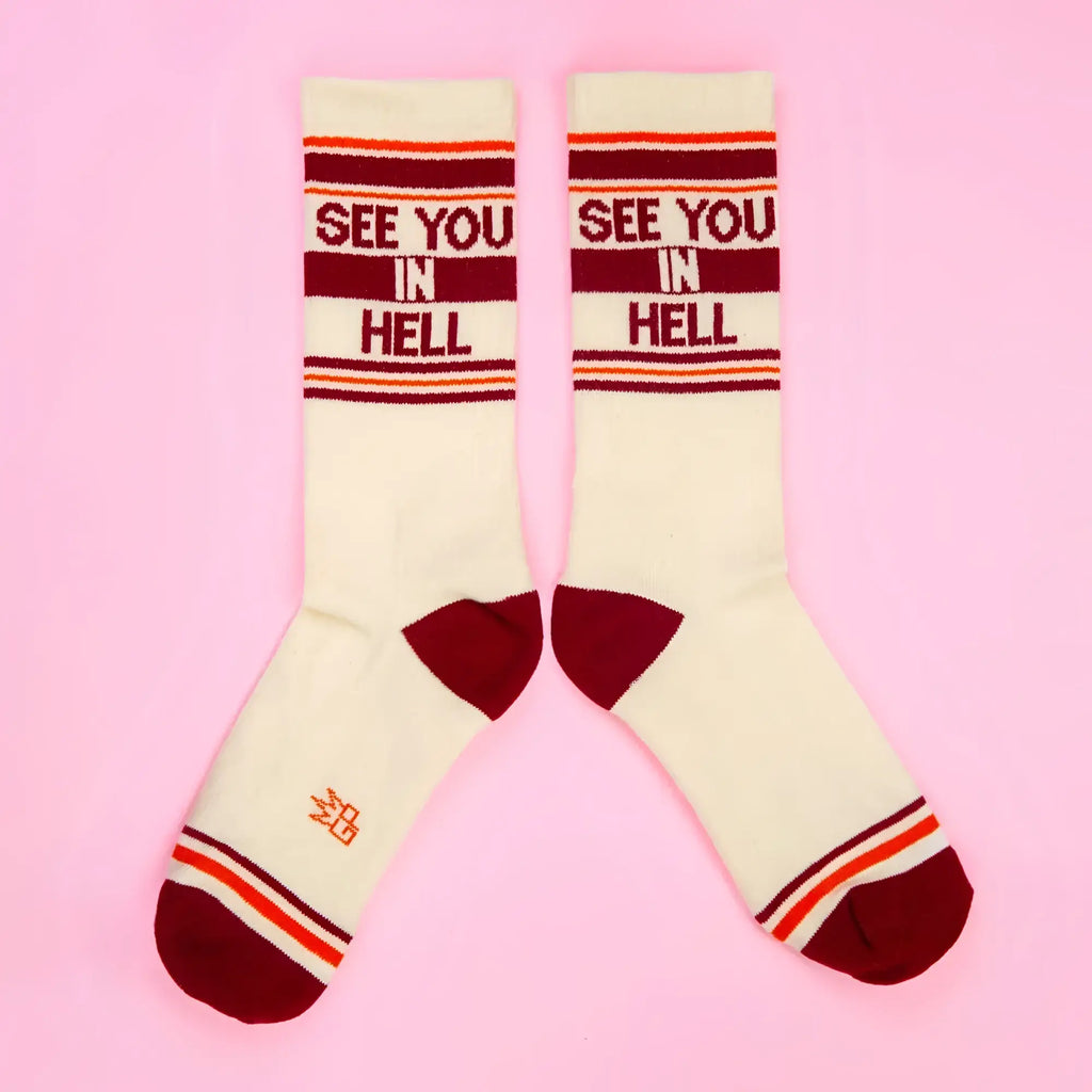 Cream-colored SEE YOU IN HELL crew socks with maroon and orange stripes and bold red lettering across the top