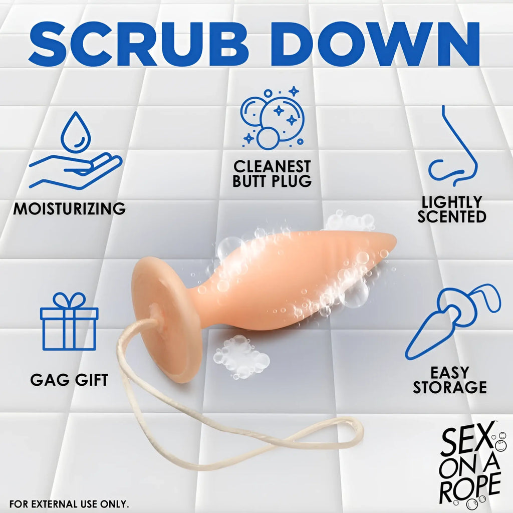 Sex on a Rope soap shaped like a peach-colored butt plug with a rope, shown with bubbles on a white tiled background.