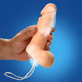 A hand holds a soapy, beige phallus-shaped Sex on a Rope Pecker Soap with a white hanging cord against a blue background.