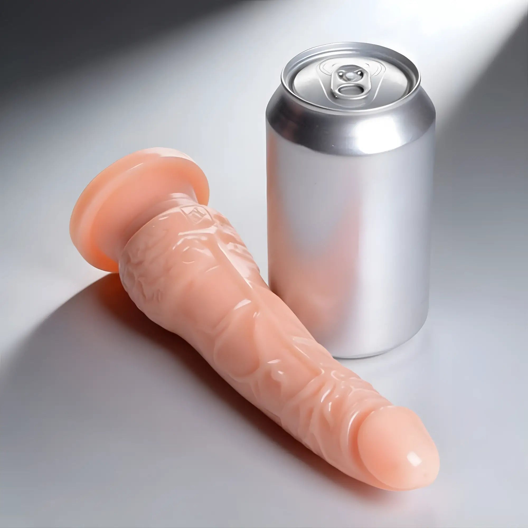 SexFlesh Lean Luke 7-inch peach-colored dildo with a suction cup base, shown next to a silver aluminum soda can.