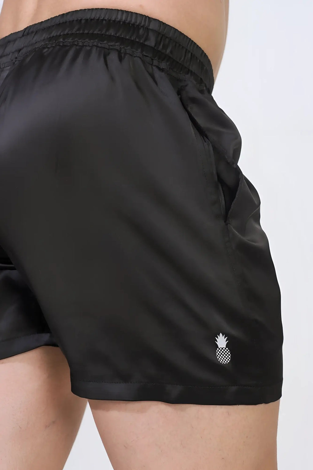 Shimmerflex active shorts in midnight black satin with a small white pineapple logo on the lower right leg