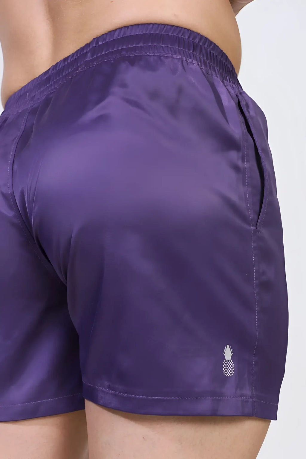 Purple satin shimmerflex active shorts with a small white pineapple logo on the lower right leg front view
