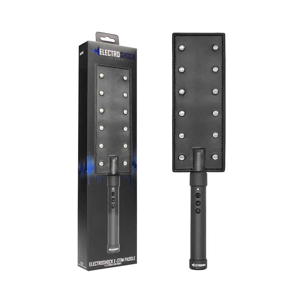 Black leather shots electroshock e-stim paddle with silver metal studs in a grid pattern on rectangular surface