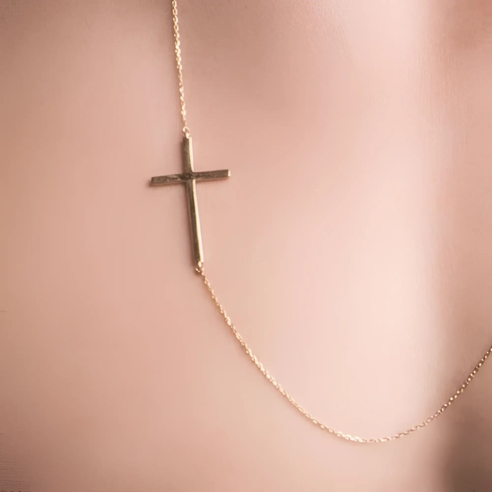 A gold-toned delicate cross necklace with a minimalist sideways design featuring slender bars and fine chain links