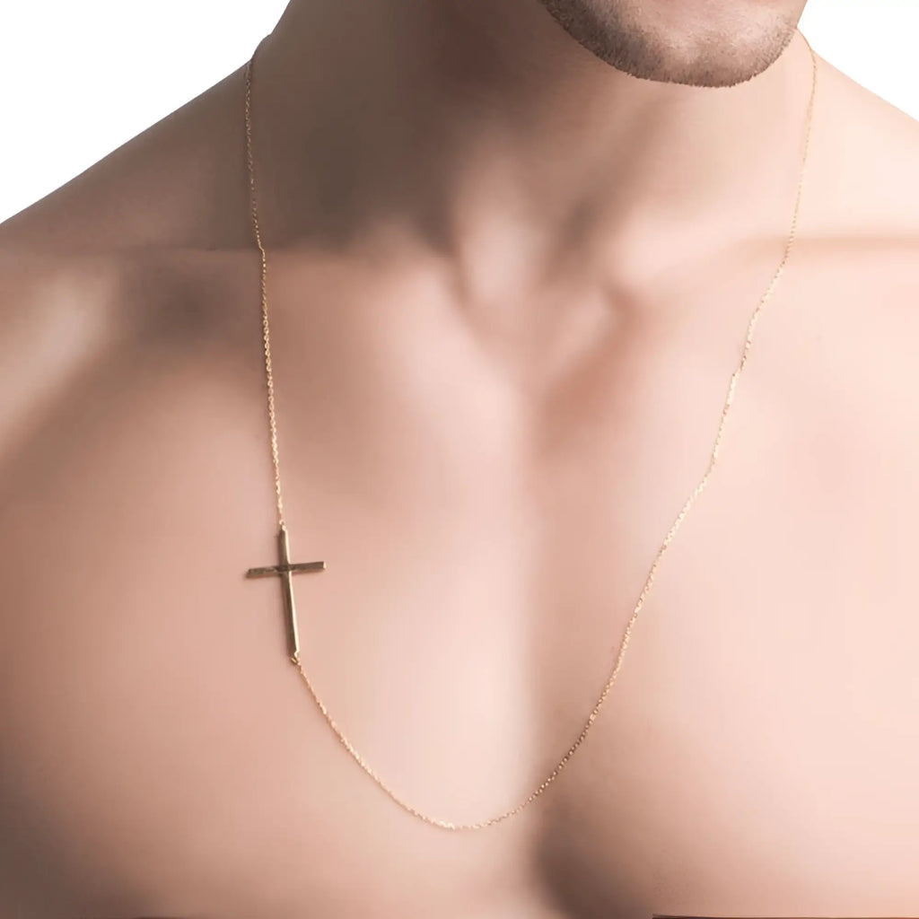 A delicate gold-toned cross pendant with a smooth metallic finish hangs from a fine chain in a sideways silver male cross necklace