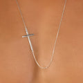 Sideways silver male cross necklace featuring a minimalist silver pendant with a delicate chain