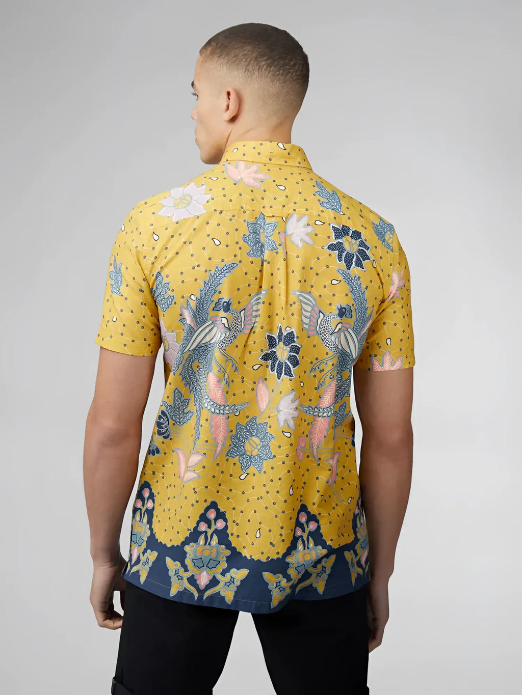 A vibrant yellow short-sleeved shirt with blue and pink floral bird patterns and a navy blue hemband in signature abstract botanical print
