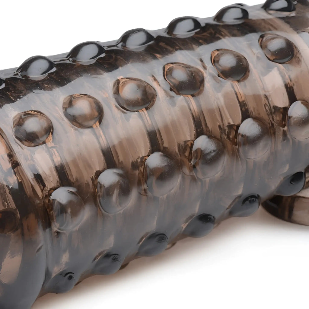 Close-up of a brown, translucent Size Matters 1.5-inch penis enhancer sleeve with a textured, studded surface.