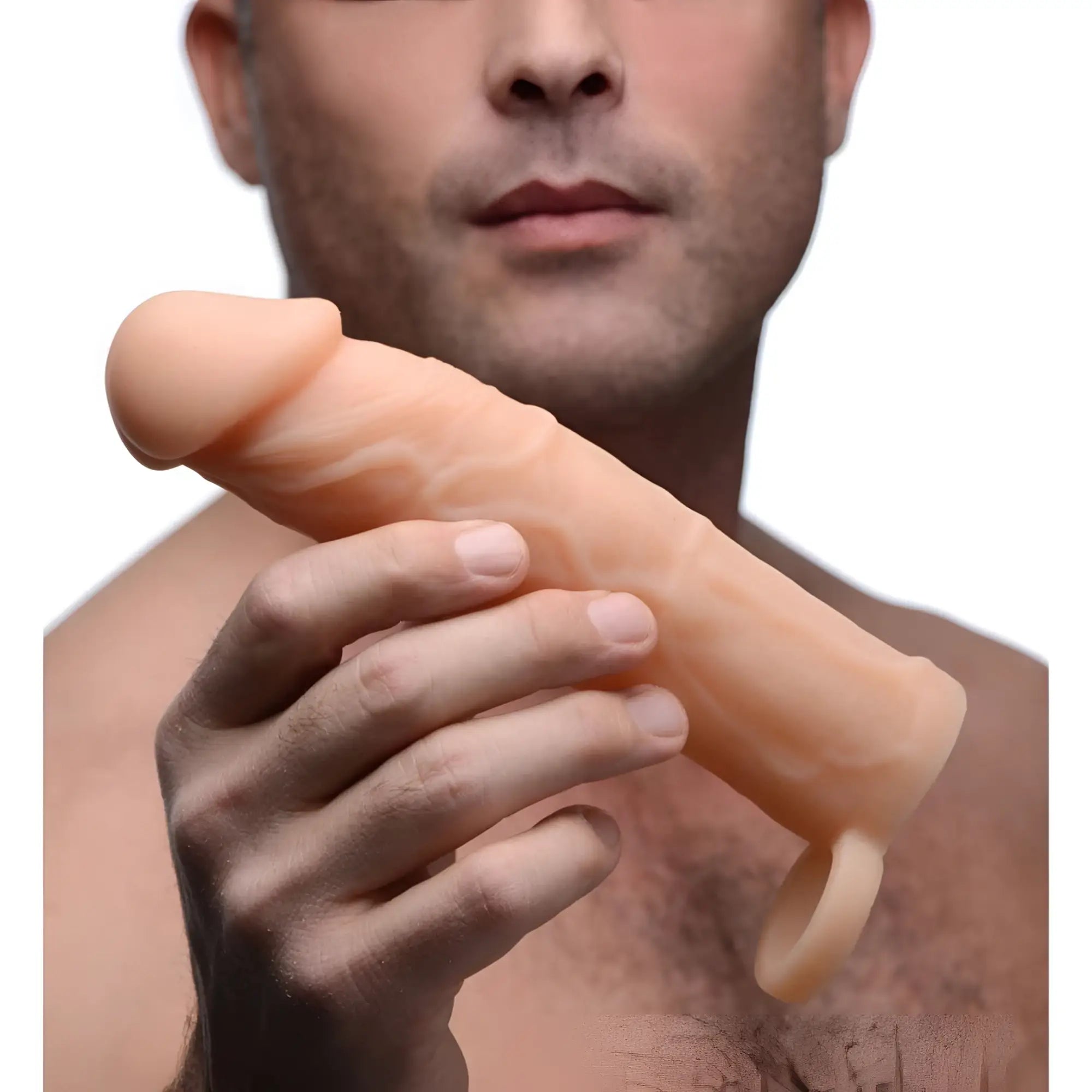 A man holds a beige, realistic silicone Size Matters 2-inch penis extension against a plain white background.