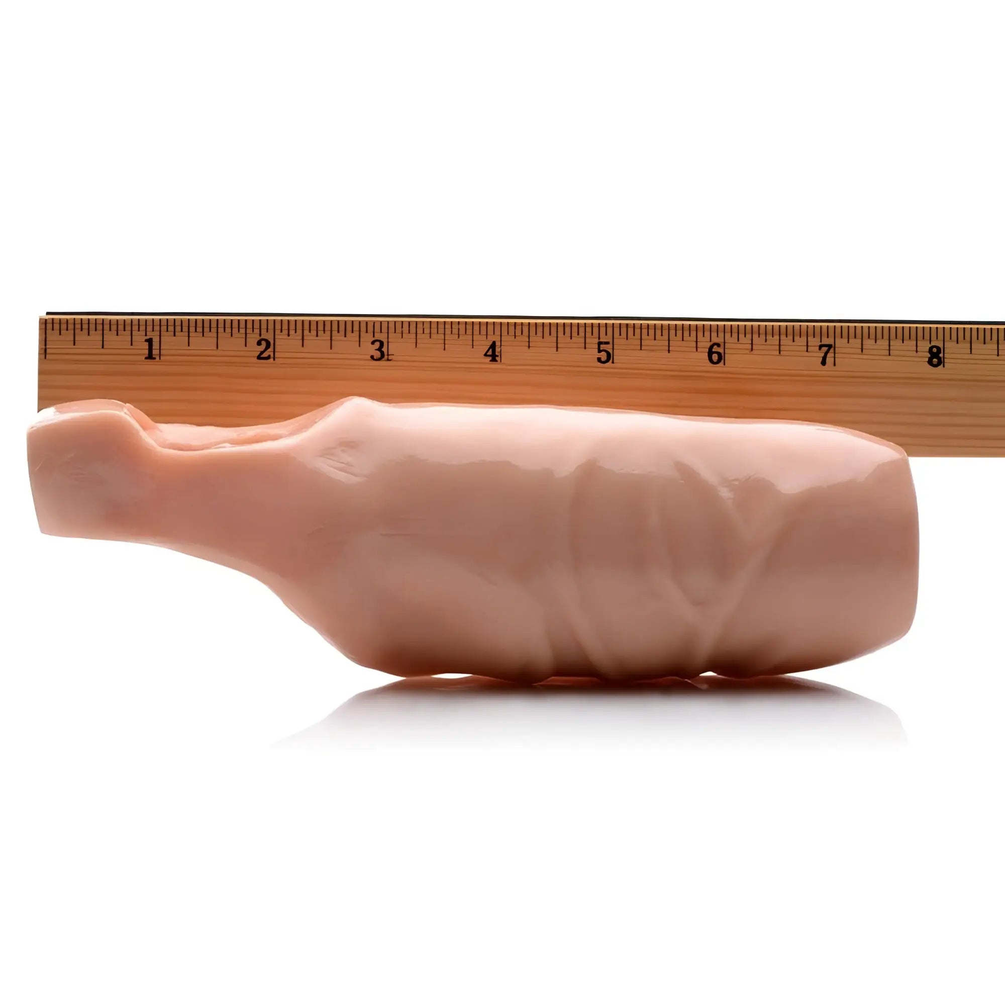 Size Matters 5-inch flesh-toned open-tip penis extension shown against a wooden ruler for scale on a white background.
