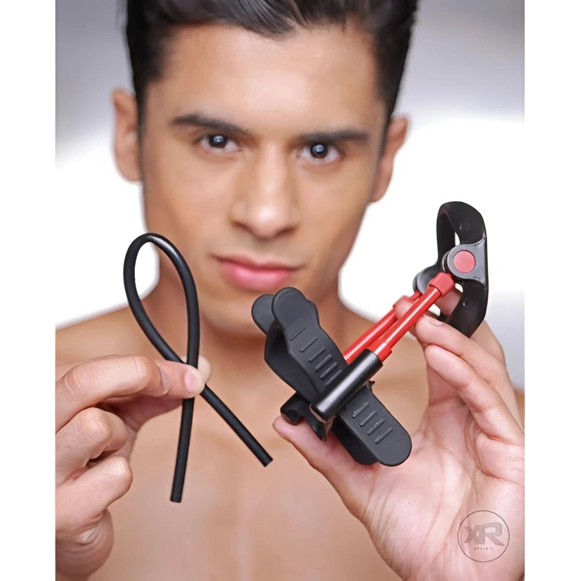 A man holds the black and red Size Matters Deluxe Penile Aide Pro device and a matching black silicone loop.