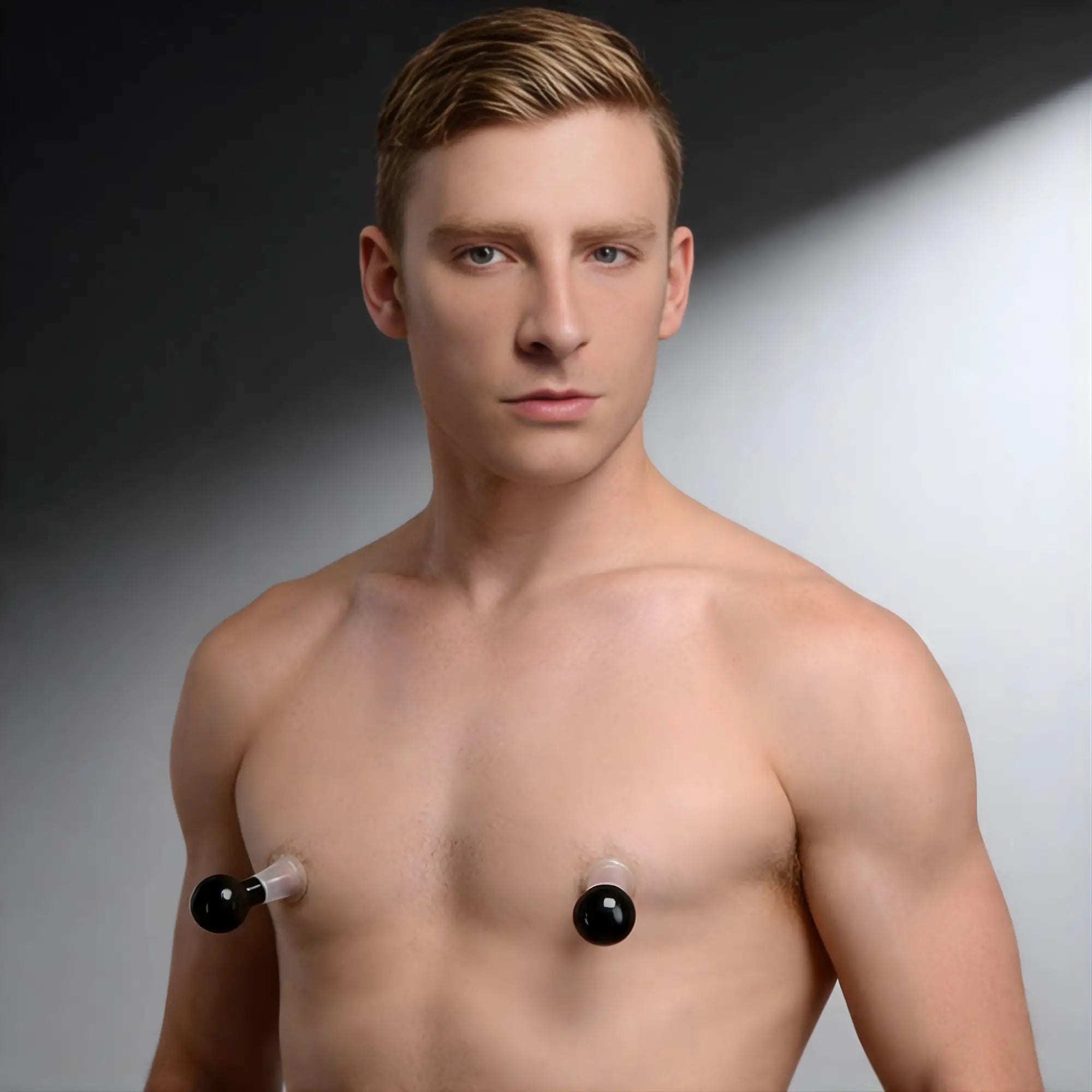 A shirtless man wearing clear and black Size Matters See Thru Nipple Boosters on a studio background.
