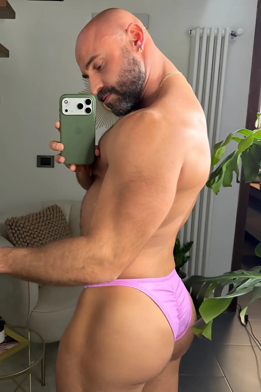 A man wearing vibrant purple soft vegan leather scrunch-butt briefs showing the back side of the product