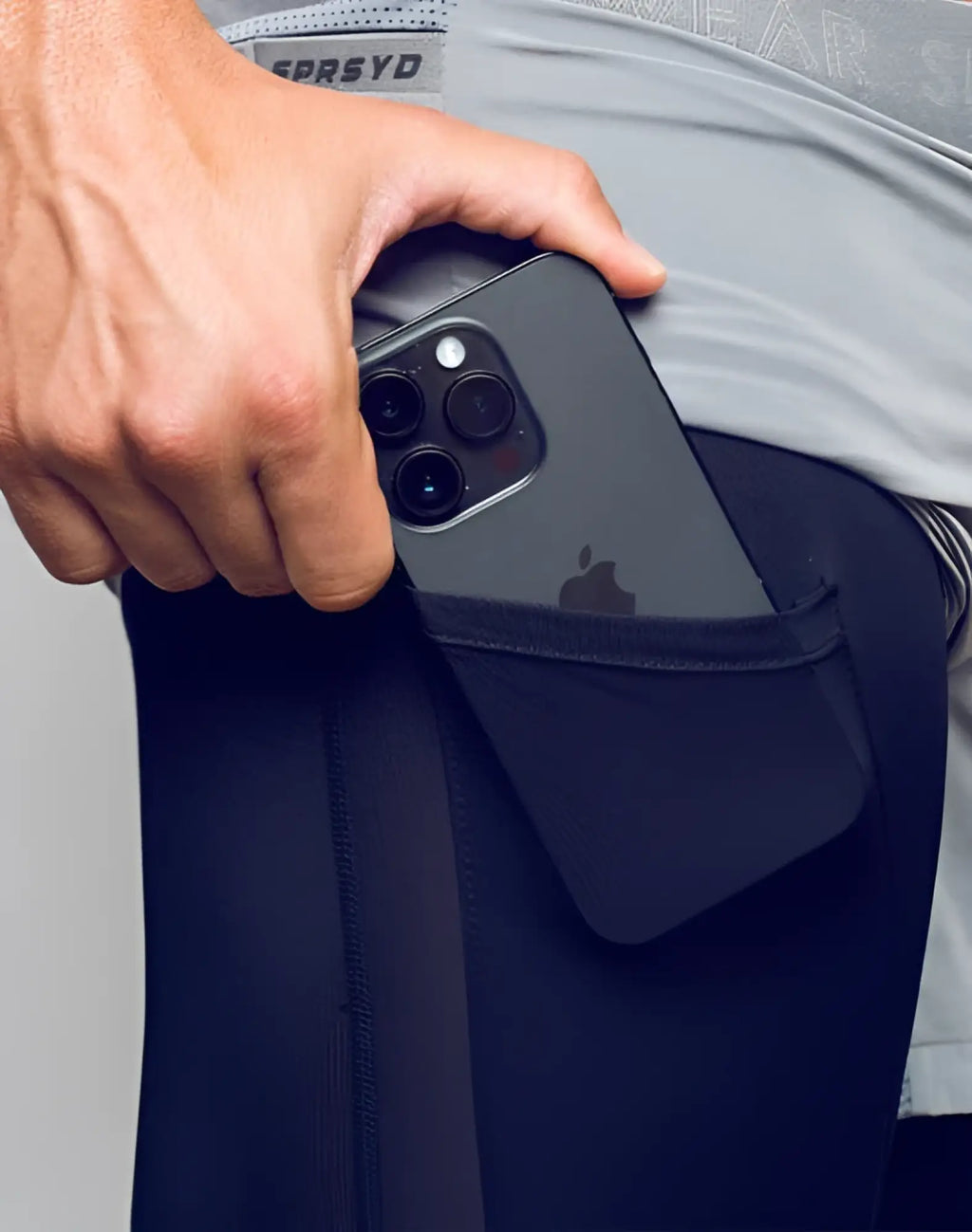 Black iphone with triple camera in pocket of dark navy spr flex short athletic leggings back view