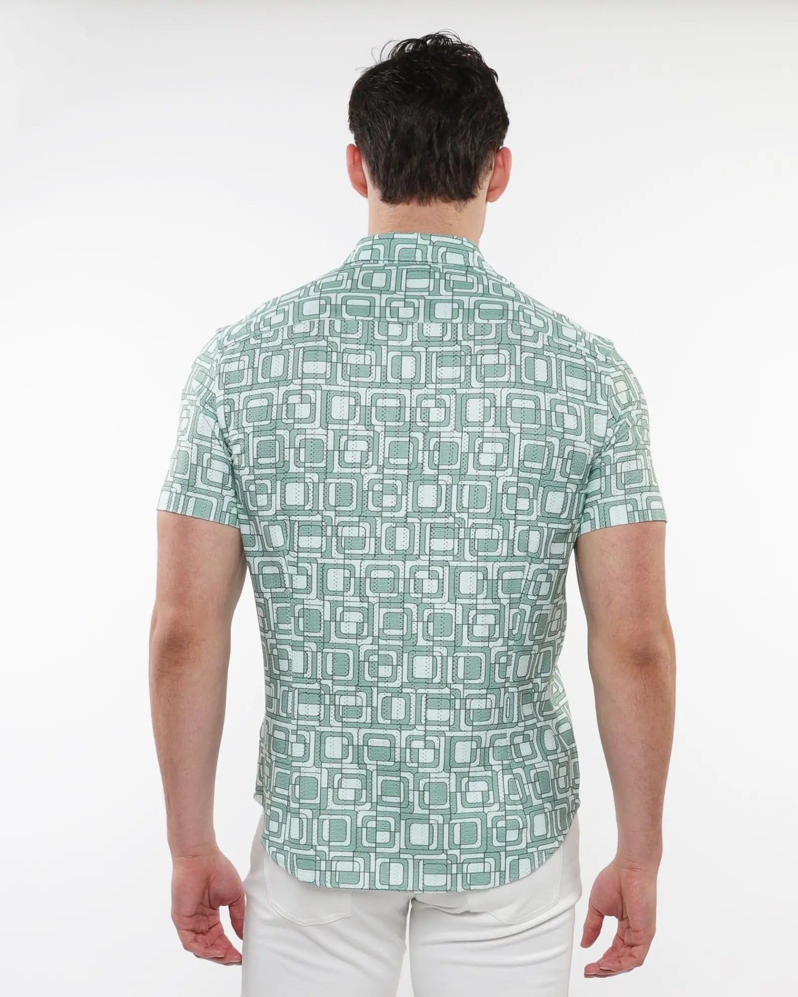 A man wearing a light green squares print open knit shirt with white and dark green geometric patterns