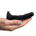 A hand holds a small, black Strap U silicone dildo with a curved shaft and flared base against a white background.