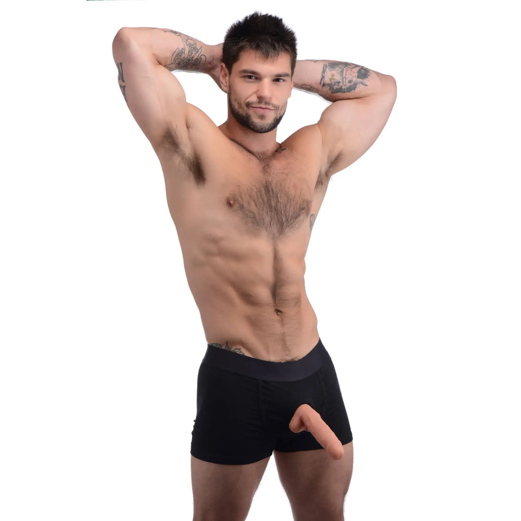 A muscular man wearing black Strap U Incognito boxer briefs with an integrated harness O-ring and a dildo attachment.