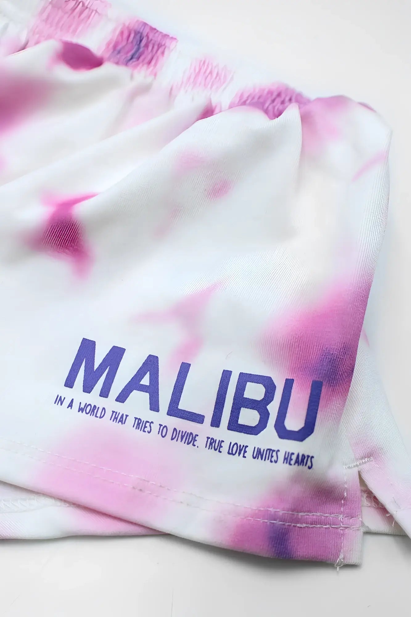 Stretch-it 2 inch short shorts in pink and white tie-dye with malibu printed in bold blue letters