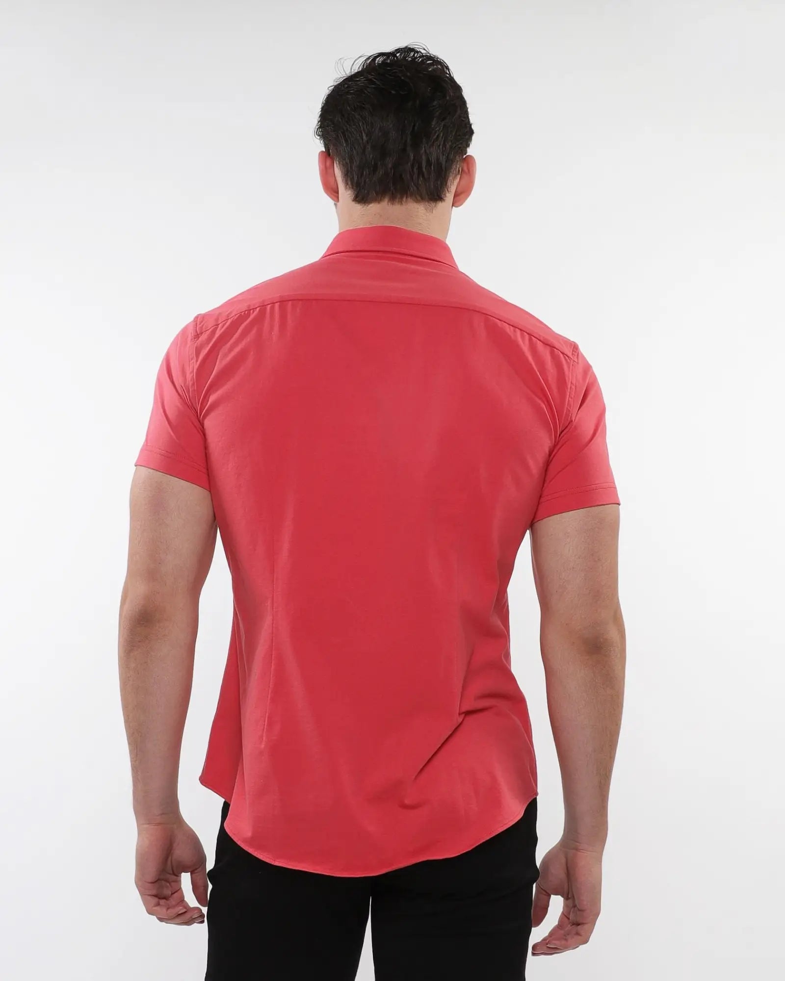 A man wearing a vibrant coral stretch knit short-sleeved shirt with tailored fit and subtle stitching details