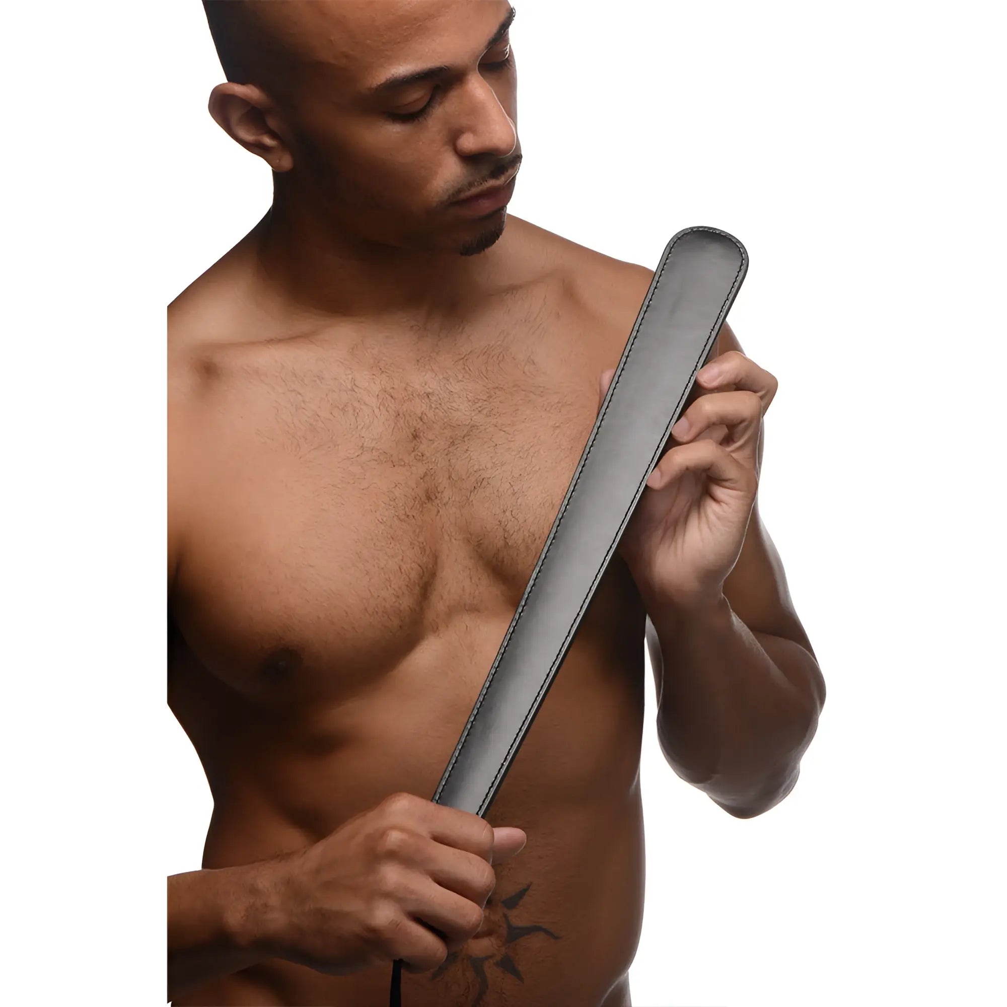 A shirtless man holds a 19-inch Strict Slapper Paddle, featuring a sleek, black leather-style design with stitched edges.